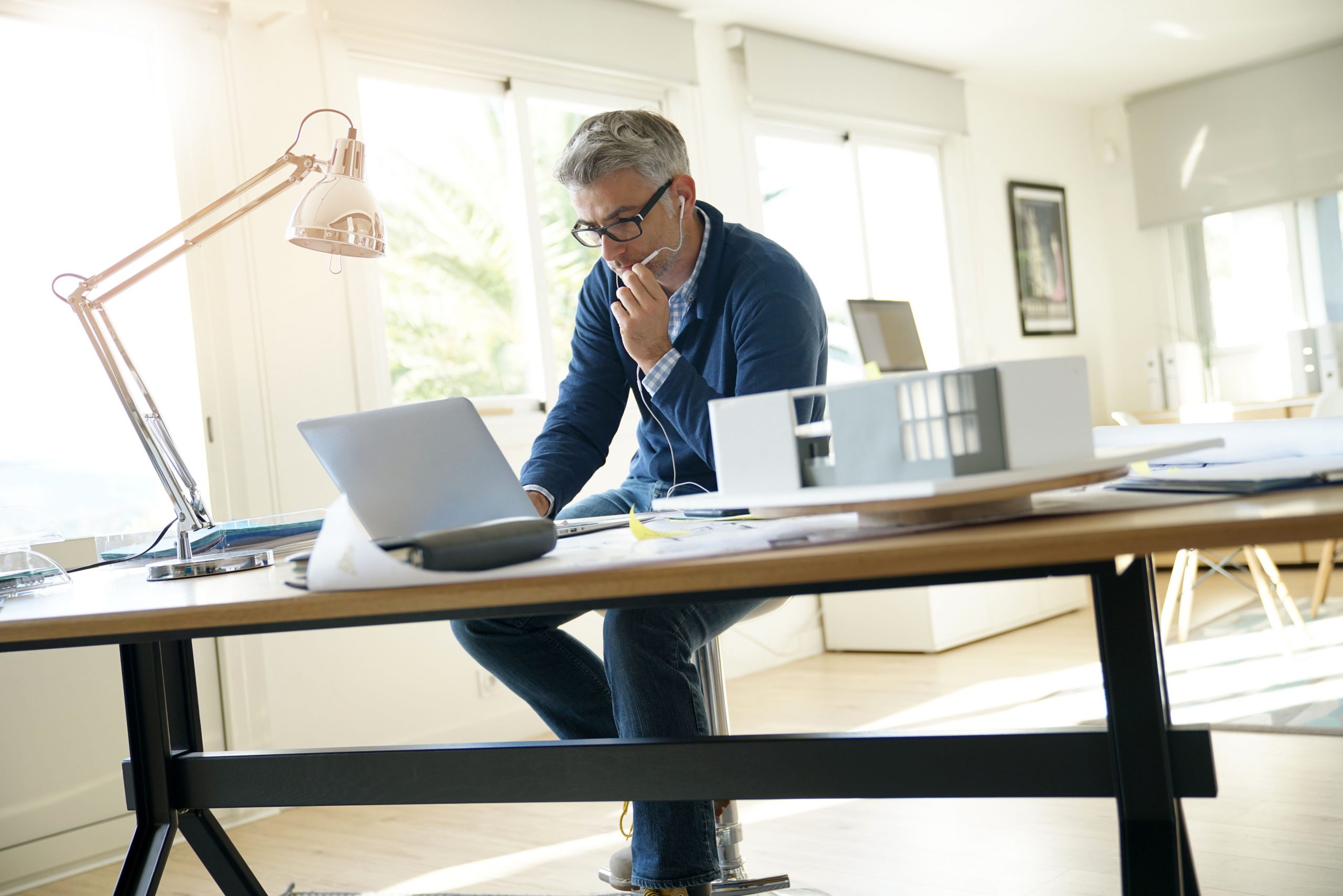 Architect in office talking to client on phone with earphones